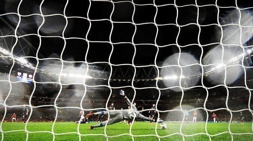 Olympiakos FC's goalkeeper Balazs Megyeri (C) dives to try and save a shot from Arsenal's Gervinho